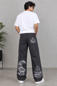 Fully embroidered washed-black baggy jeans with white ocean wave, sailing ship, and octopus embroidery